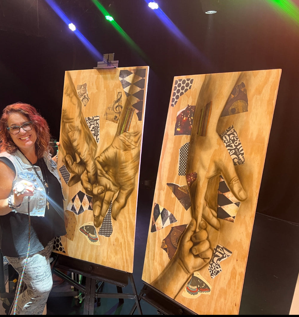 Woman standing next to two large wooden panels with artistic hand designs on a dark stage/background.