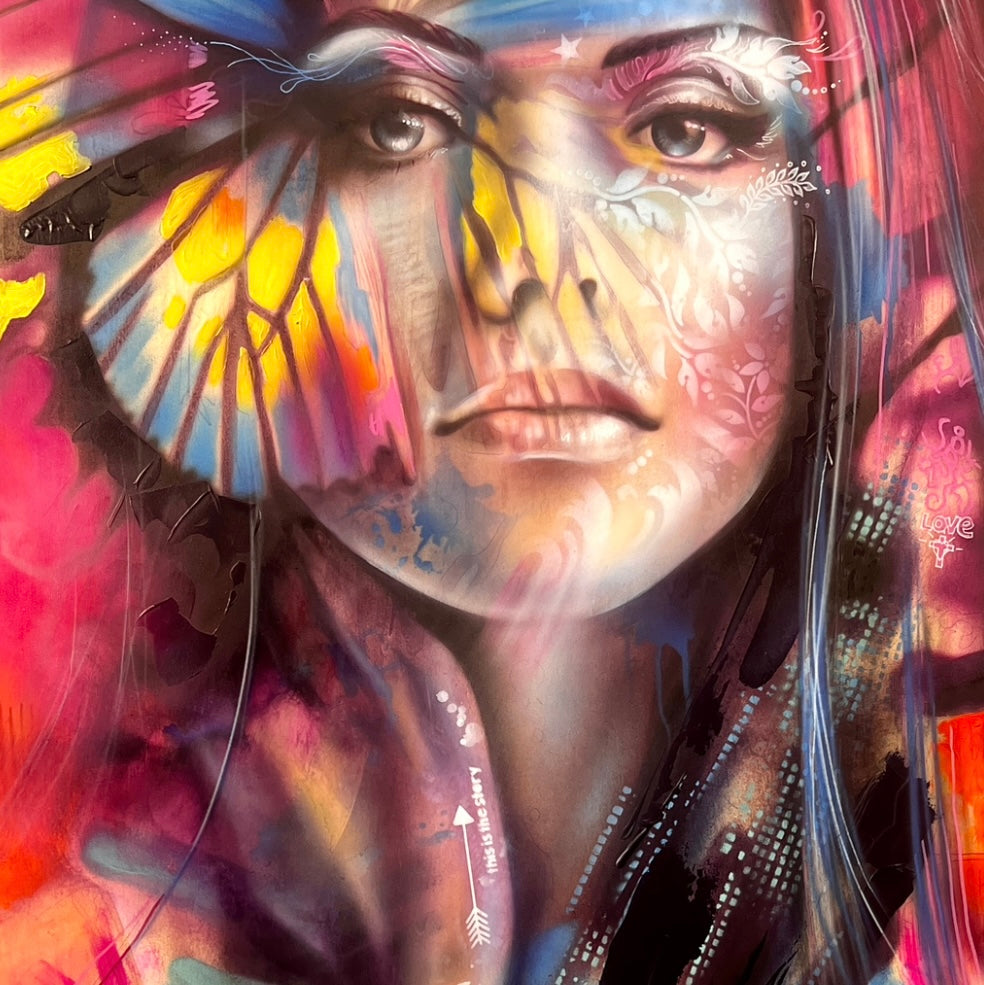 A vibrant mixed media painting on wood featuring a stylized woman's face with butterfly wings in bright colors, symbolizing spiritual transformation.