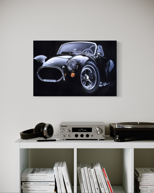 Framed black and white car artwork on a wall above a shelf with books and a radio. ac cobra limited edition canvas giclee fine art print reproduction by shenshen.