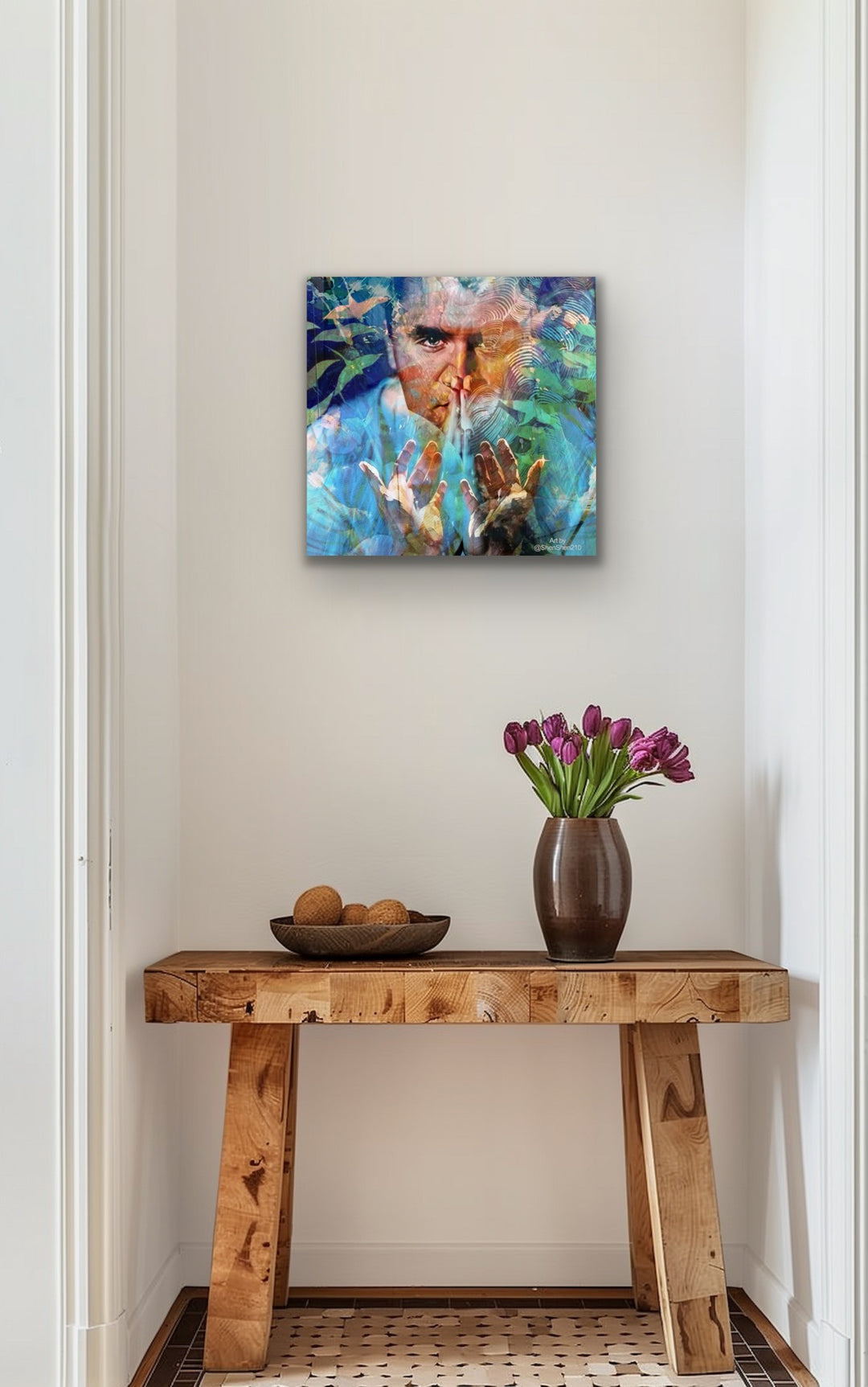 Artistic depiction of a man, charlie kirk, with a colorful background on a wall above a wooden console table with decorative items.