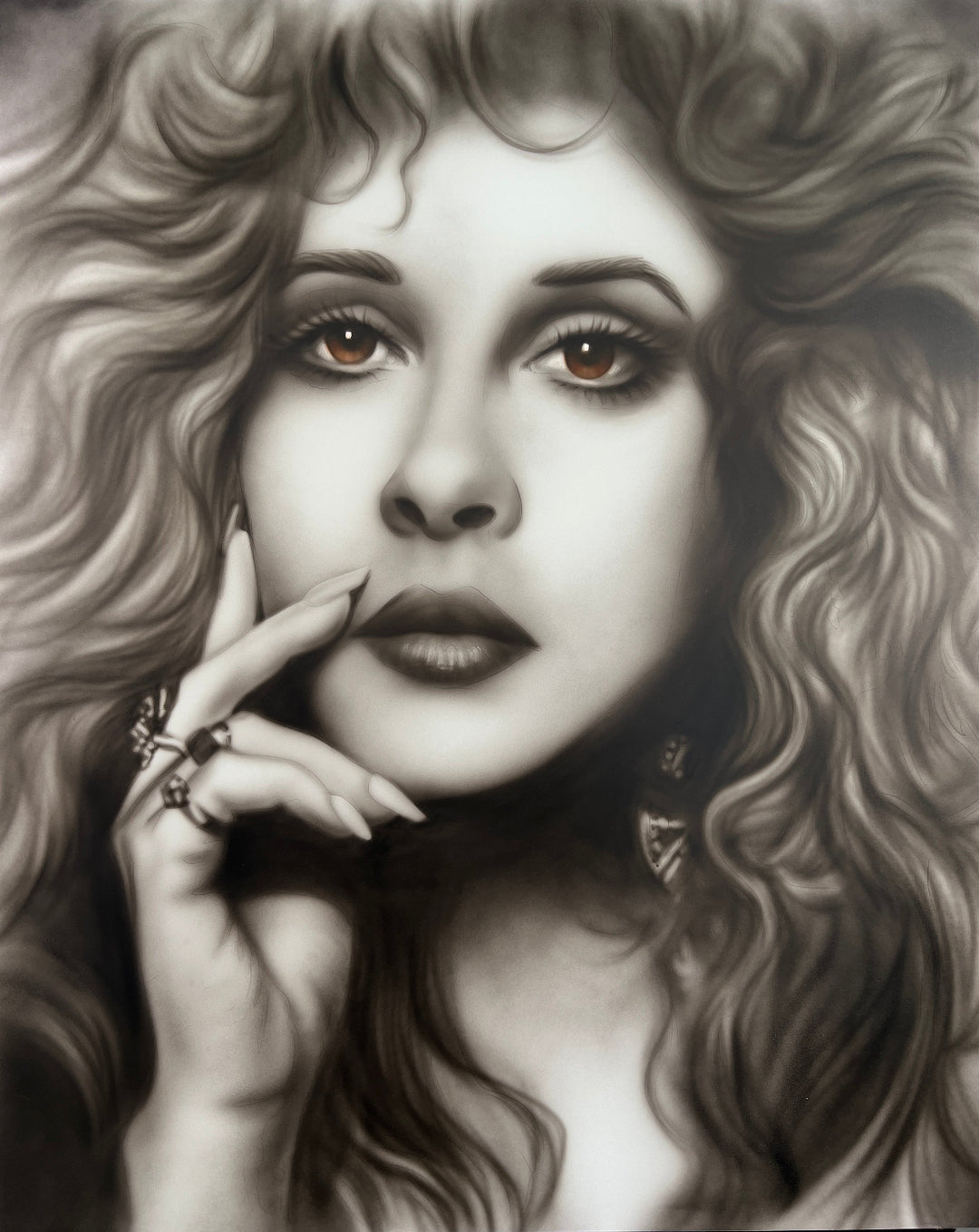 Artistic black and white portrait of a woman with curly hair and hand near her face. Monochromatic portrait of Stevie Nicks featuring flowing curls, expressive amber eyes, and soft realistic shading that captures the iconic singer-songwriter's timeless beauty and enigmatic presence.