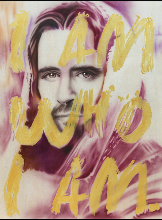 A canvas giclée print featuring a portrait of Jesus with the words 'I AM WHO I AM' written in bold letters across the image, in gold and multicolored hues.